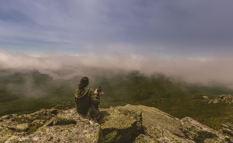 Georgia looks out over foggy mountains with her dog.